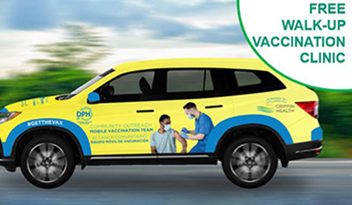 Car driving with promotion for vaccine clinic on wrap