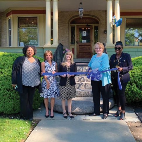Bridge employees cutting a ribbon to celebrate opening of Mosaic Parenting Center