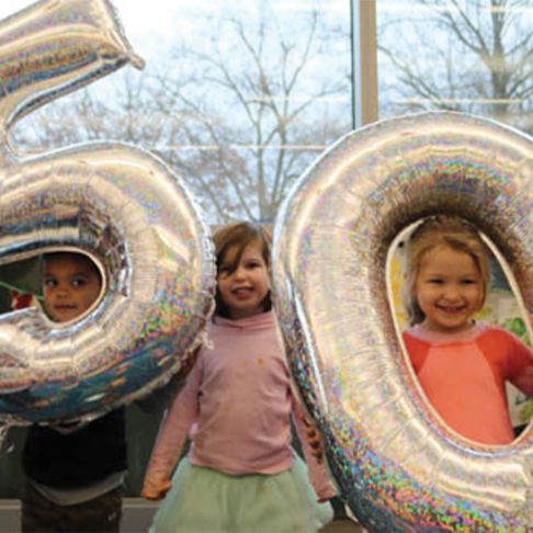 Children holding balloons that say "50"