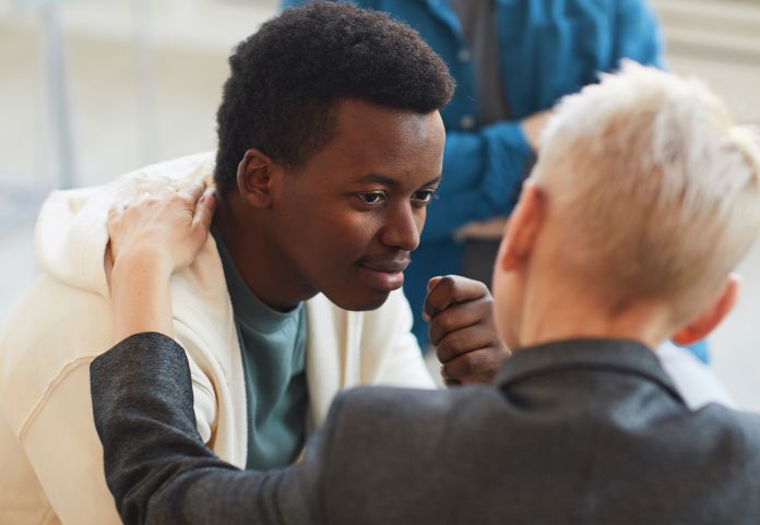 Man with supportive hand on teenagers shoulder