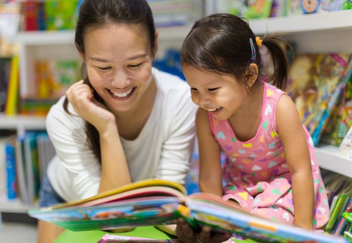 Mother and daughter reading a book in a library