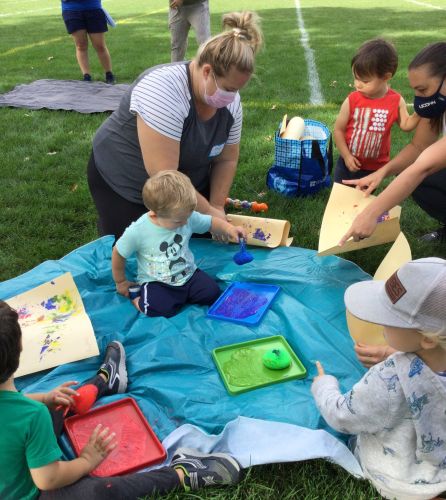 Mothers helping children with craft outside 