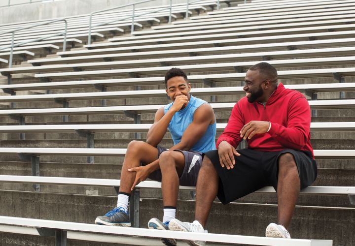 Coach and teenager sitting on bleachers