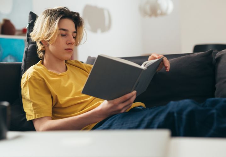 Teen reading book on couch